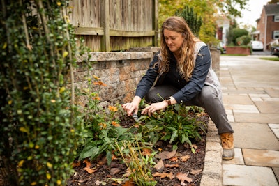 woman clipping weeds in flower garden