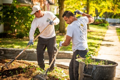 Two lawn care professionals landscaping a yard