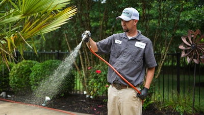 Lawn care professional spraying lawn treatment