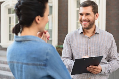 Man with clipboard speaking to woman