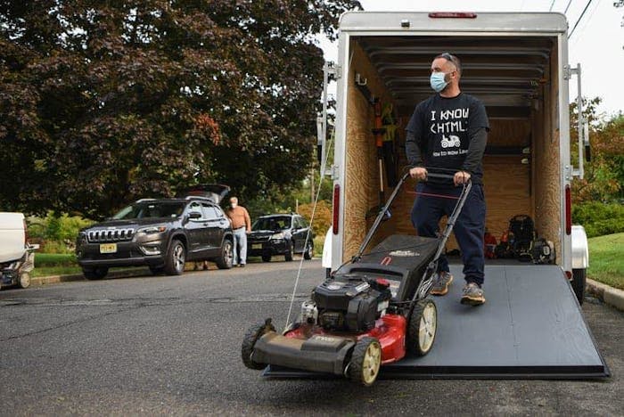 man unloading lawn mower off landscaping truck