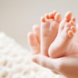 A hand holding a newborn’s feet