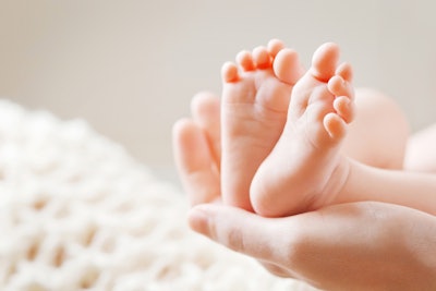 A hand holding a newborn’s feet