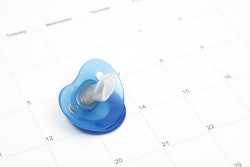 A pacifier laying on a desktop calendar