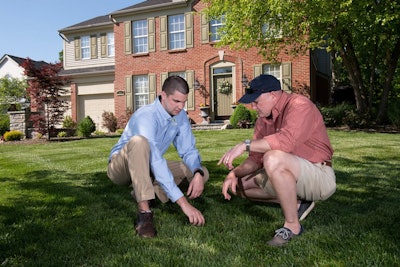 Landscape professional and client discussing the grass on front lawn