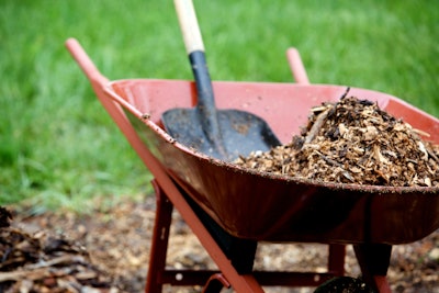 red wheelbarrow with pile of mulch in it and shovel