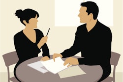 man and woman at desk discussing paperwork
