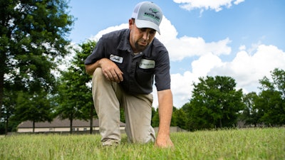 Master Lawn technician kneeling on grass
