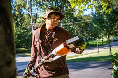 terren landscapes employee replacing the battery on a string trimmer