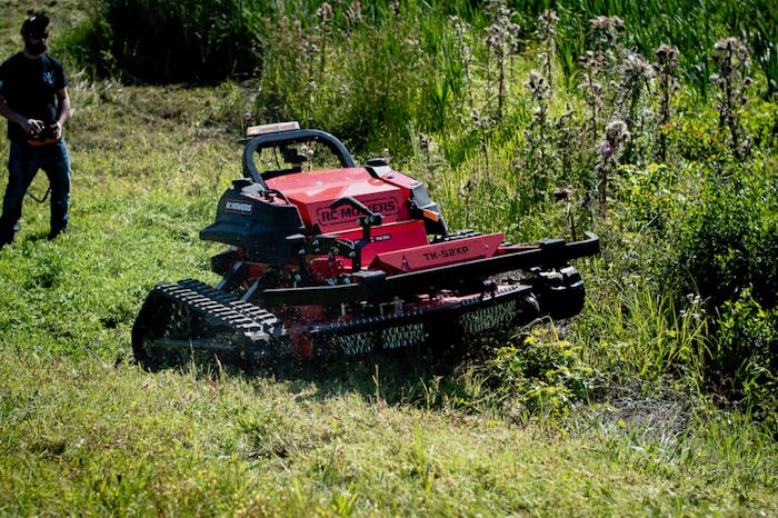 Man mowing thick brush using RC Mowers TK-52XP remote-operated robotic mower.