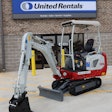 Takeuchi TB20e electric compact excavator parked in front of a United Rentals store.