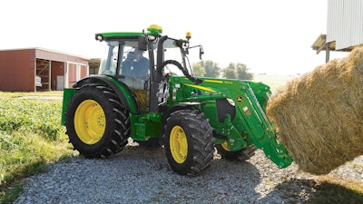 John Deere 5M Series tractor hauling a hay bale