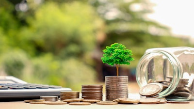 tree growing out of a stack of coins near a mason jar of coins