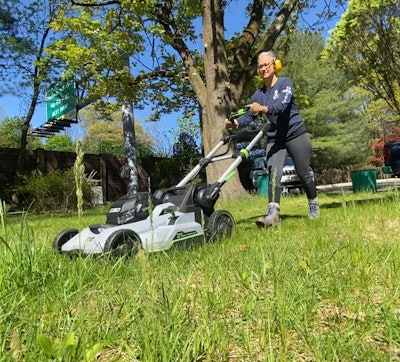 Nicky Atansio cutting grass with a push mower