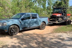 Light Blue 2022 Ford Maverick towing ATV on trailer on dirt road