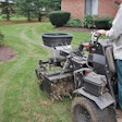 A landscaper using a lawn aeration machine on a lawn
