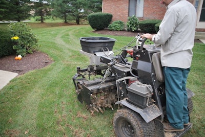 A landscaper using a lawn aeration machine on a lawn