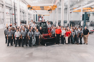 Takeuchi employees stand next to a compact track loader manufactured in Moore, South Carolina