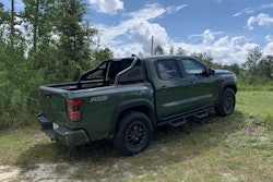 2022 Nissan Frontier Pro-4X pickup truck tactical green color side view parked on grassy hill with trees in background
