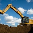Cat 320 Electric Excavator dumping a bucket of dirt