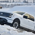white Ford F-150 Lightning driving up snow bank