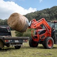 kioti hx series tractor loading a bale of hay