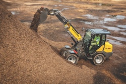 New Holland ML35T small articulated loader boom extended dumping mulch on pile
