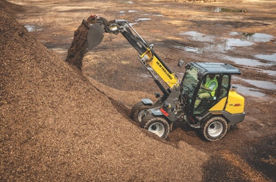 New Holland ML35T small articulated loader boom extended dumping mulch on pile