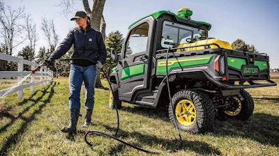 woman spraying fence next to new gator UTV