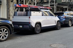 white TELO MT1 electric pickup truck with ladder on top tool boxes in bed at urban construction site