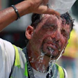 Construction worker pouring bottle of water over head