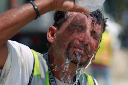 Construction worker pouring bottle of water over head