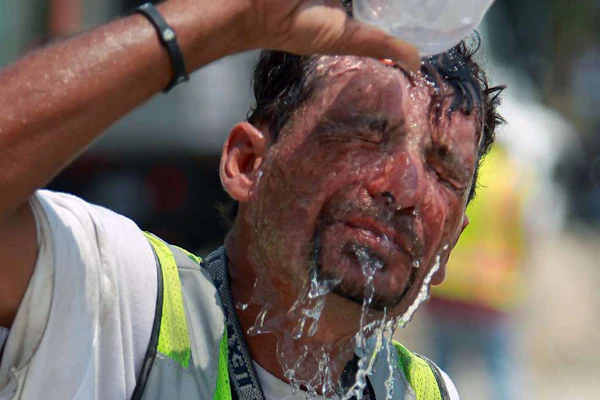 Construction worker pouring bottle of water over head